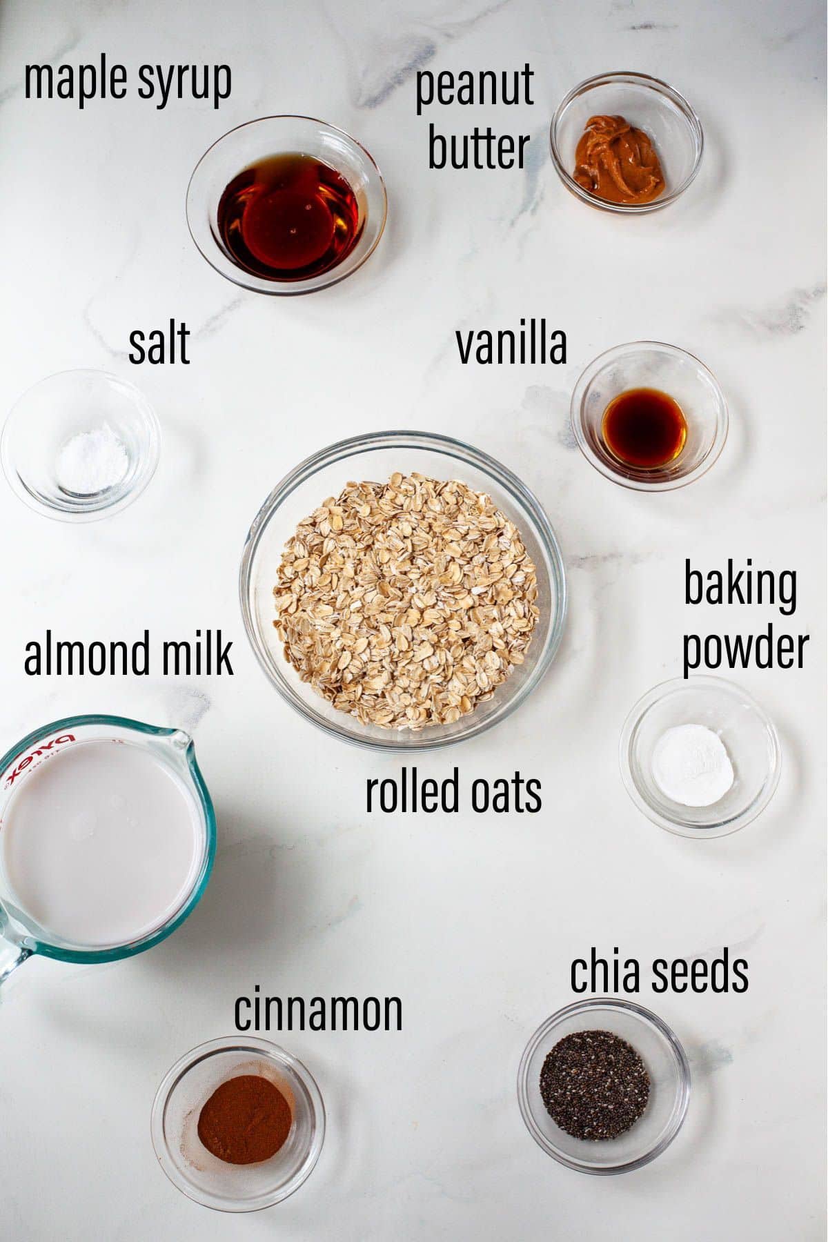 ingredients for vegan baked oatmeal laid on marble surface with black text overlay for each